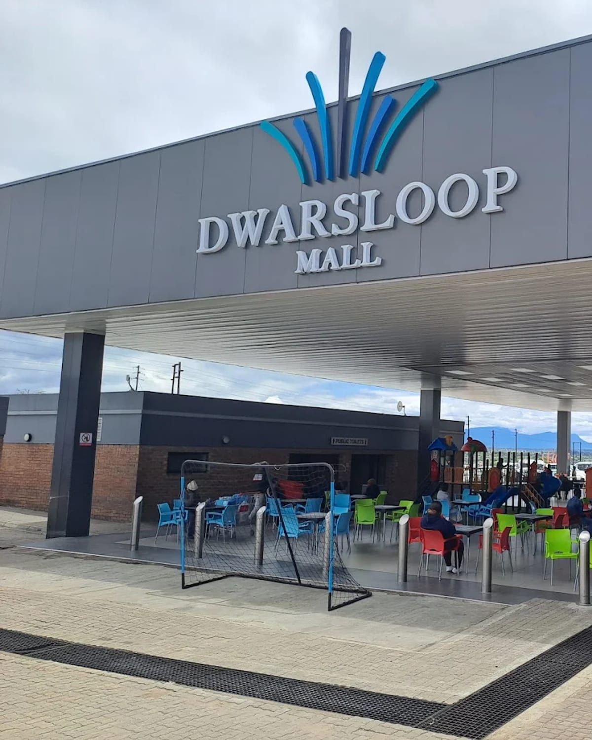 The entrance to Dwarsloop Mall, with covered walkway and seating outside the shopfronts